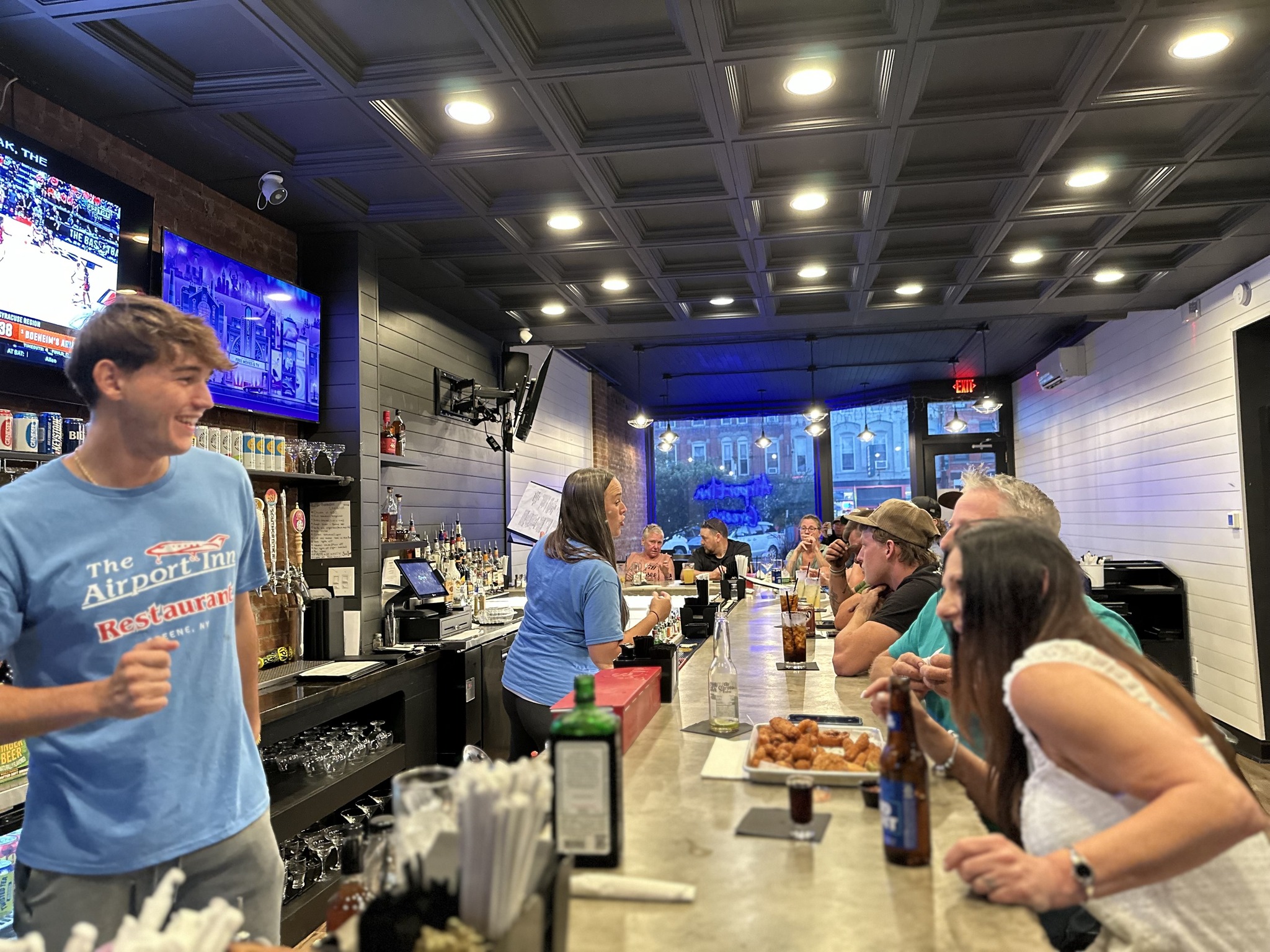 Greene bar interior busy with customers seated at the bar under warm lighting