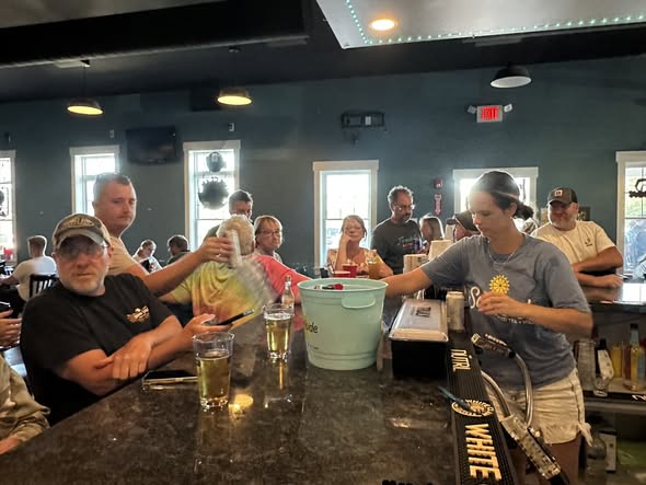 Bartender serving at the crowded bar during daytime with a community atmosphere