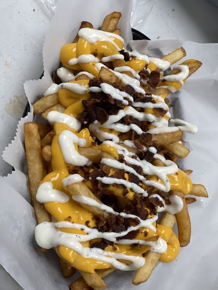 Loaded fries with bacon bits, cheese sauce, and ranch drizzle