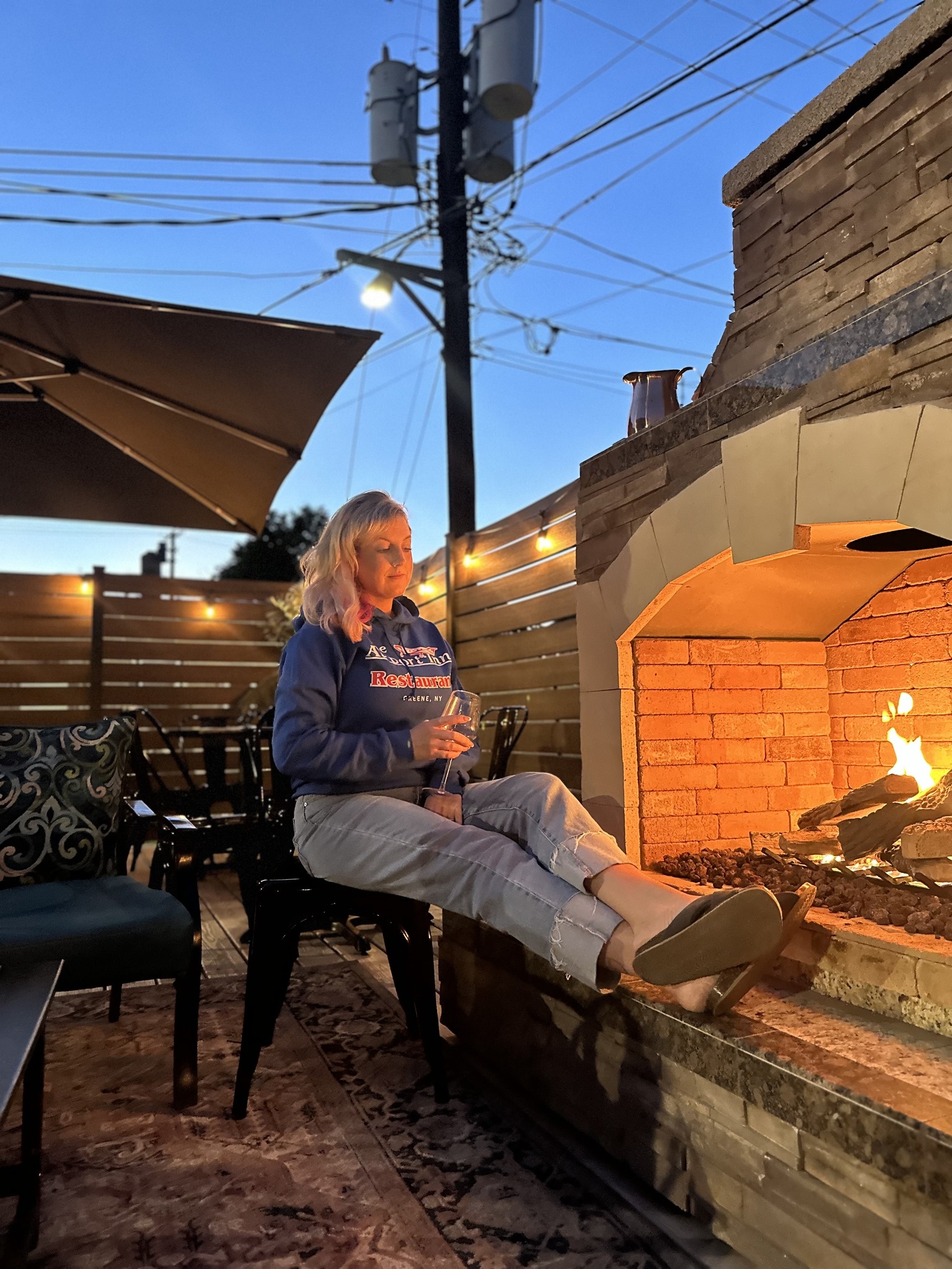 Greene patio at evening with gas fireplace lit and cozy string lights