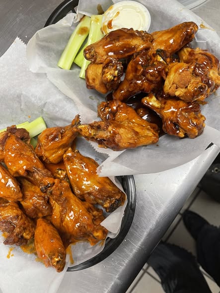 Bourbon glazed bone-in wings in a basket with celery and dipping sauce